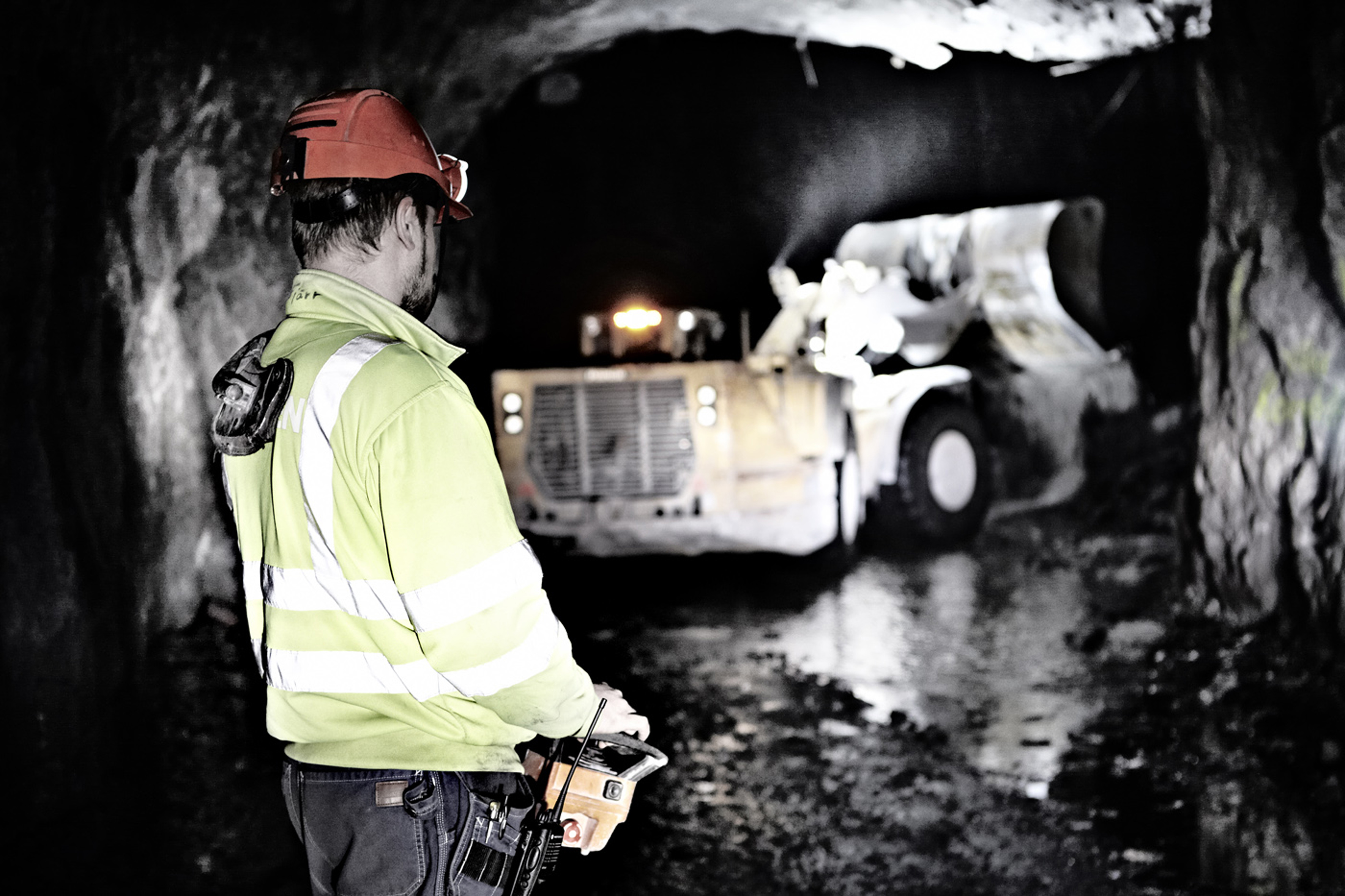 Man i varselkläder fjärrstyr en anläggningsmaskin under jord i gruvan i Garpenberg