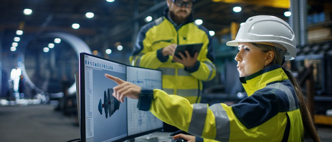 Worker in front of computer screens in an industrial environment