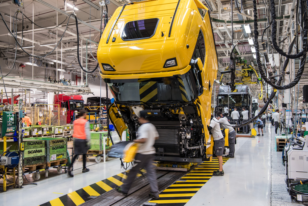 Workers assembling truck chassis at an assembly line